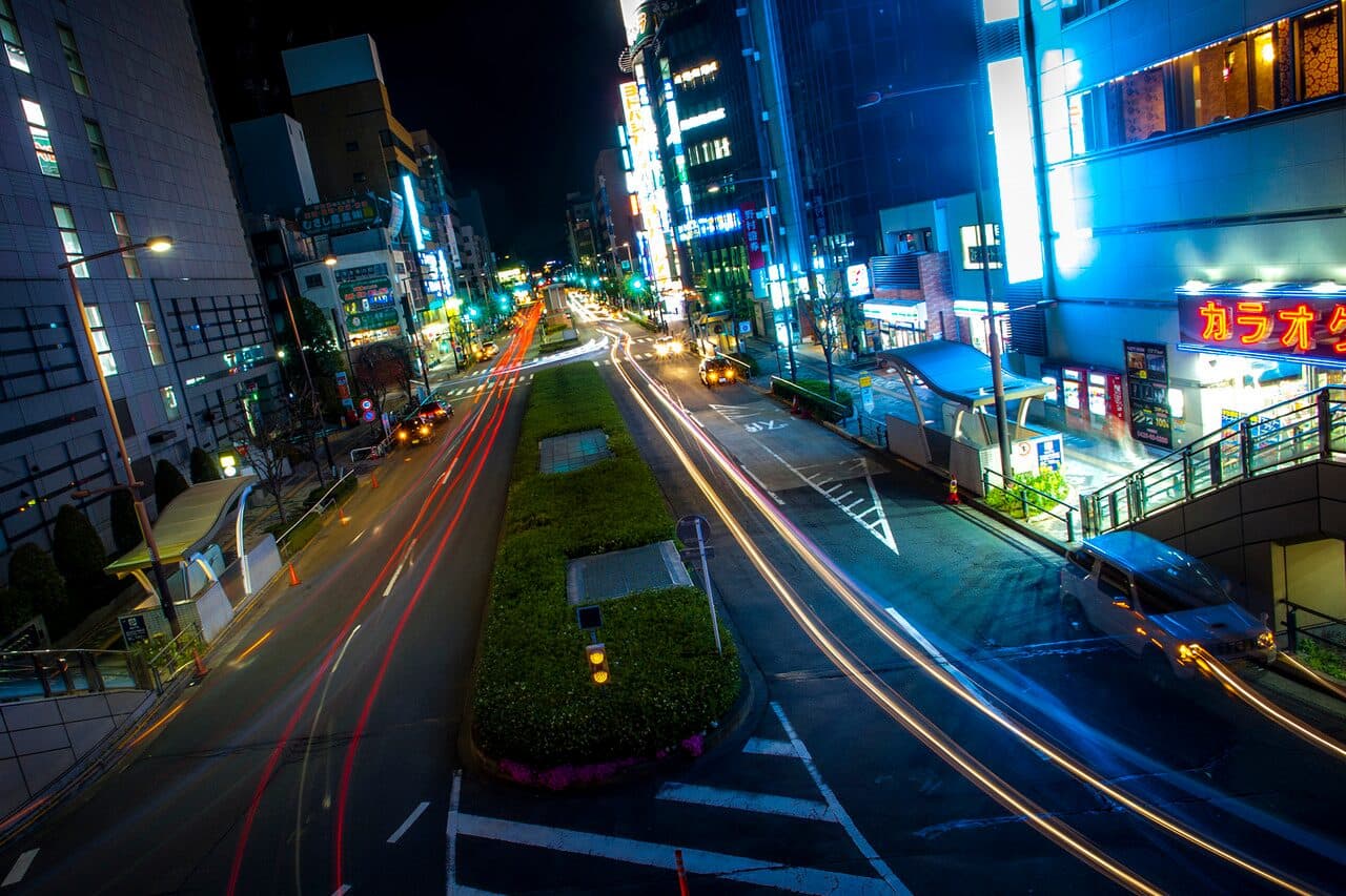 Hachioji's main boulevard at night, lit by neon signs and car light trails