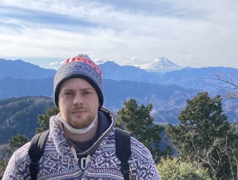 Luke on the summit of Mount Takao, with snow-capped Mount Fuji behind him
